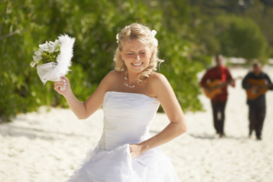 Gorgerous bride walking to wedding ceremony on the beach with bouquet. Beautiful hawaii wedding. Tropical carribean wedding moments.